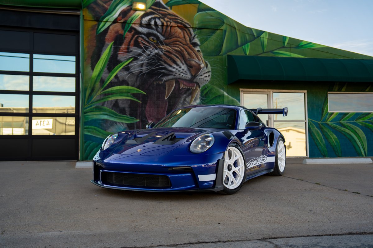 2025 Porsche 911 GT3 RS in blue with white rims and "GT3 RS" livery.