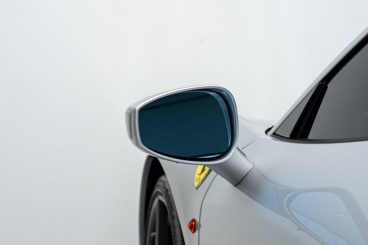 Close up of a silver 2015 Ferrari 458 Speciale side mirror with blue tint.