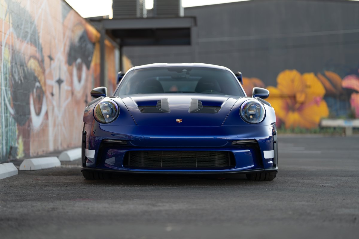 Front view of a 2025 Porsche 911 GT3 RS in blue, featuring aggressive aero and vents.