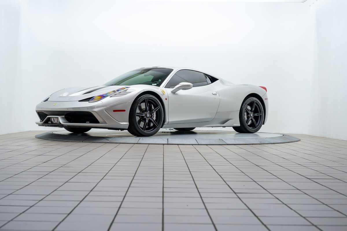 Silver 2015 Ferrari 458 Speciale with black rims and a racing stripe livery.