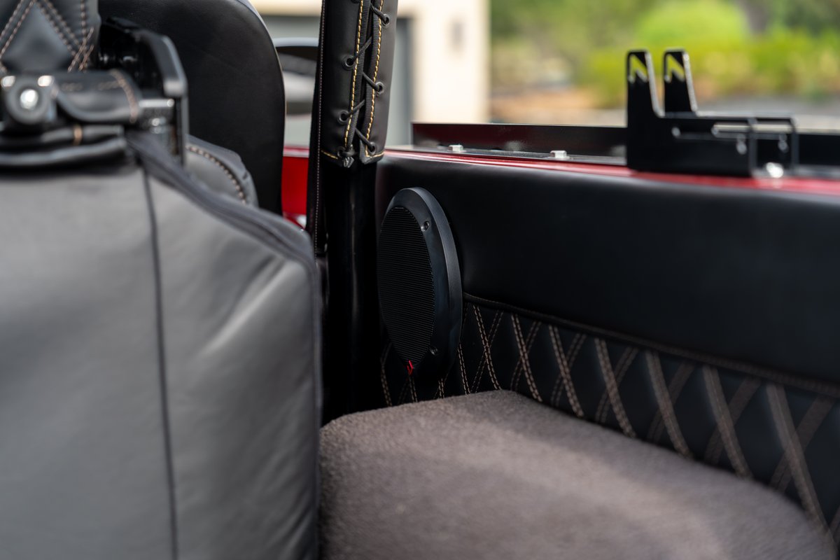 Custom interior of a red 1966 Ford Bronco by Atlas Broncos, showing diamond-stitched trim and a speaker.