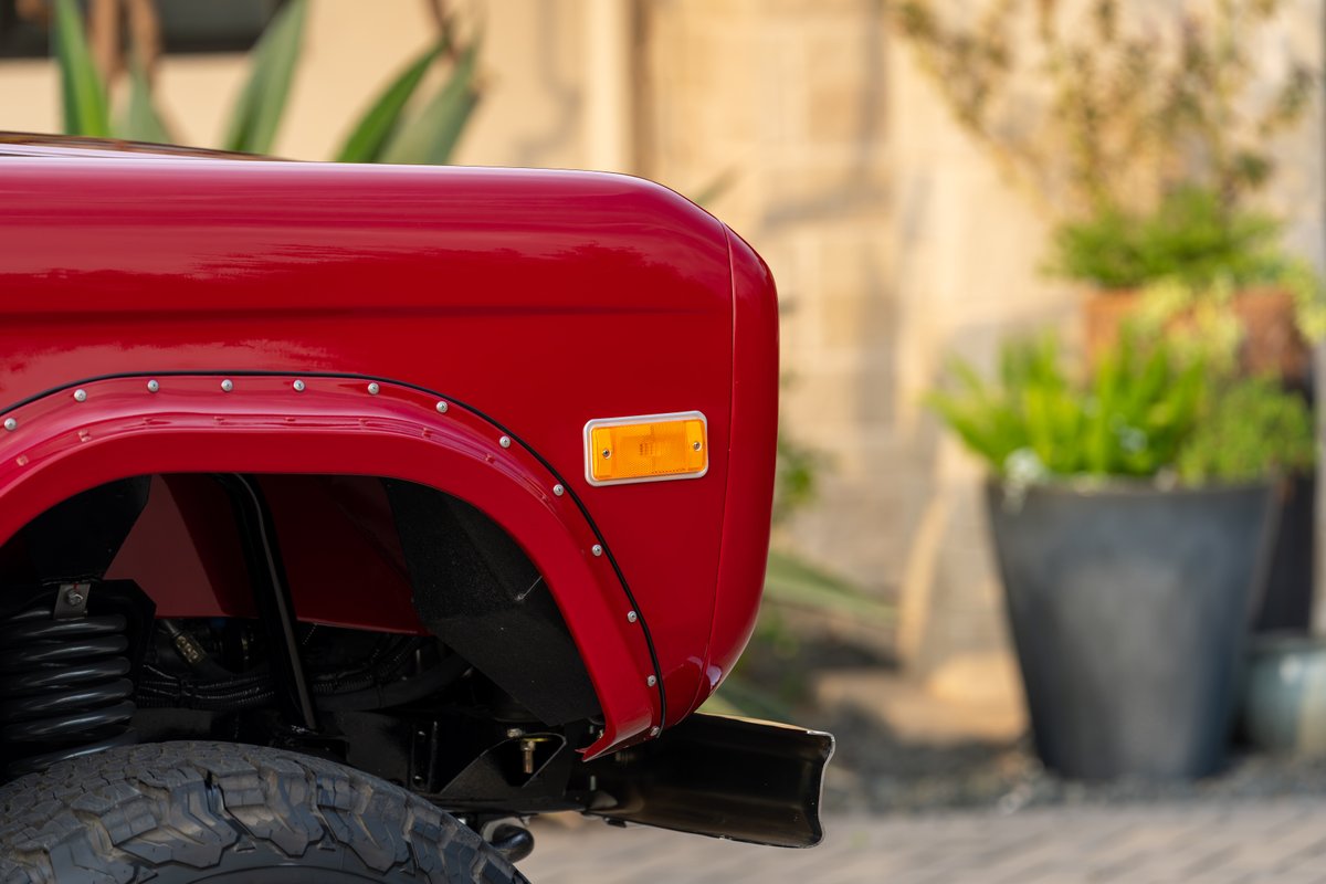 Red 1966 Ford Bronco with riveted fender flares and amber turn signal.