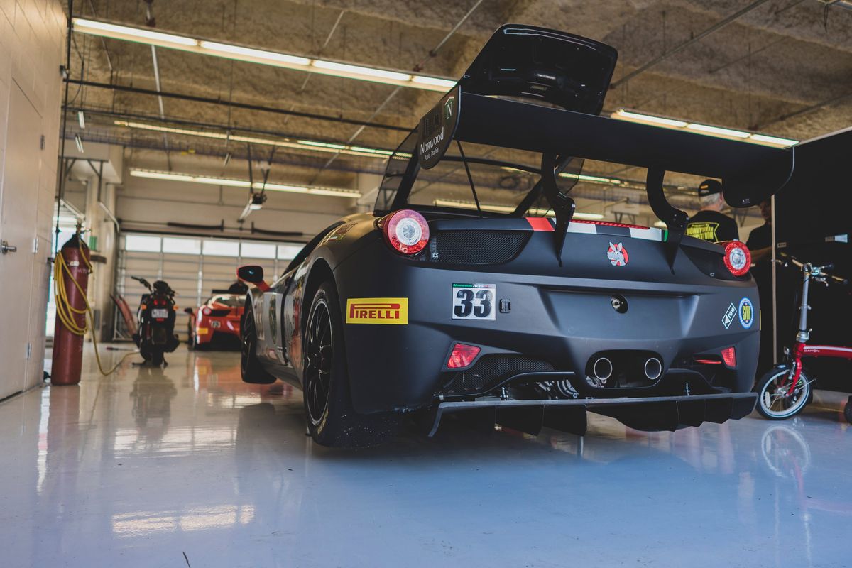 Matte black Ferrari 458 Challenge #33 race car in pit. Features a large carbon fiber wing, aggressive diffuser, and Pirelli slicks.