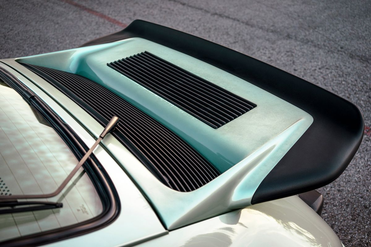 Close-up of a 1976 Porsche 930's ice metallic green whale tail spoiler with black lip and engine cover louvers.