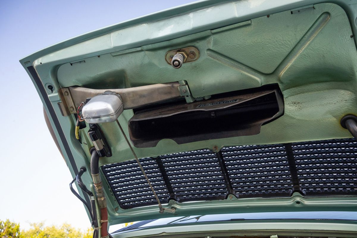 Ice metallic green 1976 Porsche 930 rear decklid underside, featuring engine bay light, "Precision" sticker, and cooling grille.