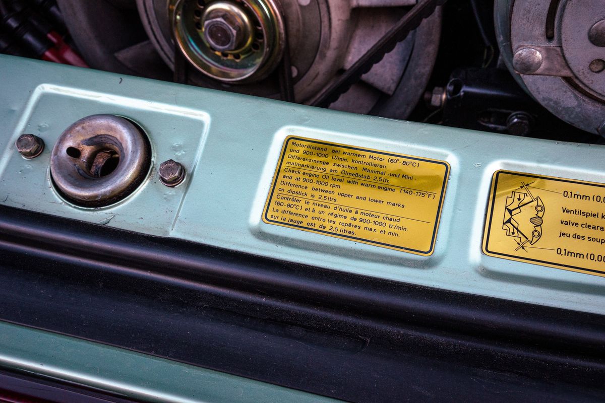 Ice Metallic Green 1976 Porsche 930 engine bay. Focus on engine oil spec decal, valve clearance sticker, and vintage mechanicals.