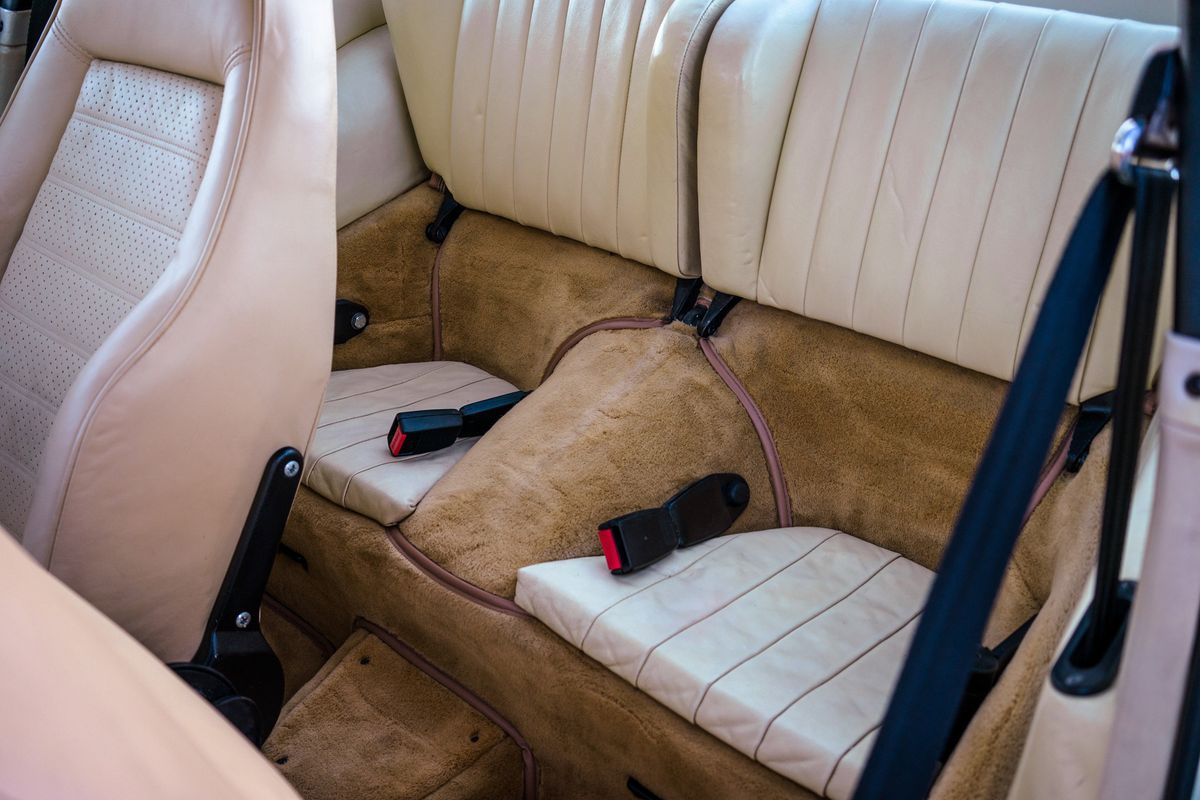 Classic 1976 Porsche 930 interior. Light cream leather rear seats, perforated front seat, and tan shag carpet.