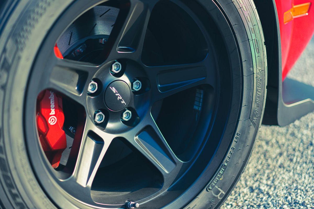 Red Dodge SRT's matte black multi-spoke rims, red Brembo calipers, drilled rotors, and Pirelli performance tire.