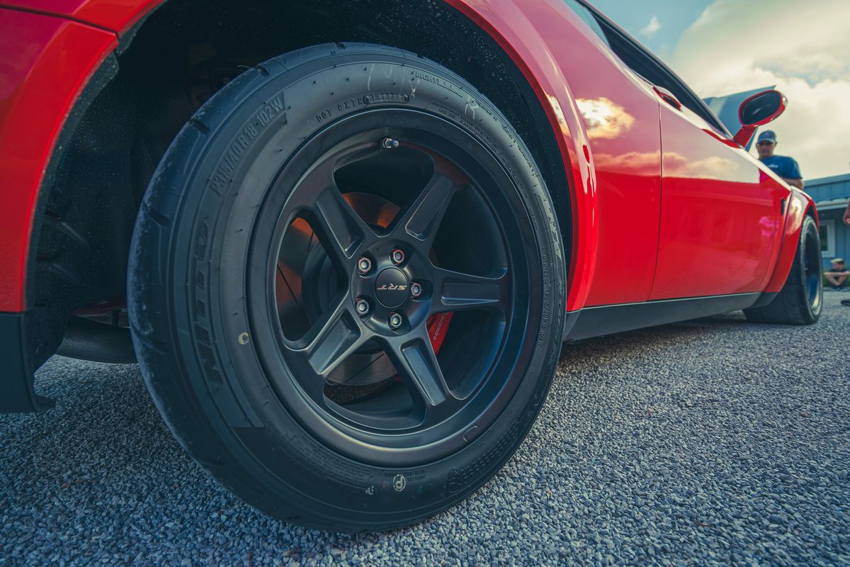 Red Dodge Challenger SRT Widebody close-up: black 18-inch SRT wheels, P315/40R18 tires, and red Brembo calipers.
