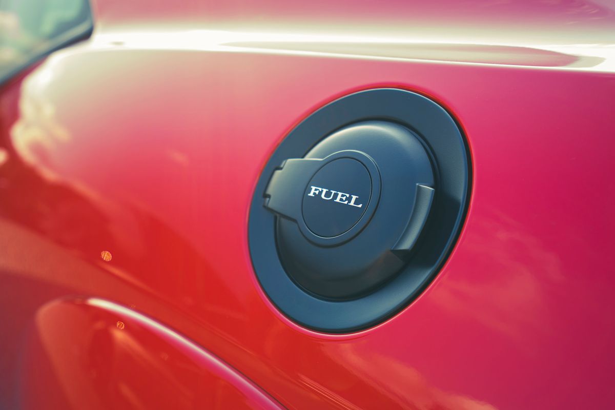 Close-up of a vibrant red Dodge Challenger's matte black fuel filler cap, featuring "FUEL" embossed lettering.