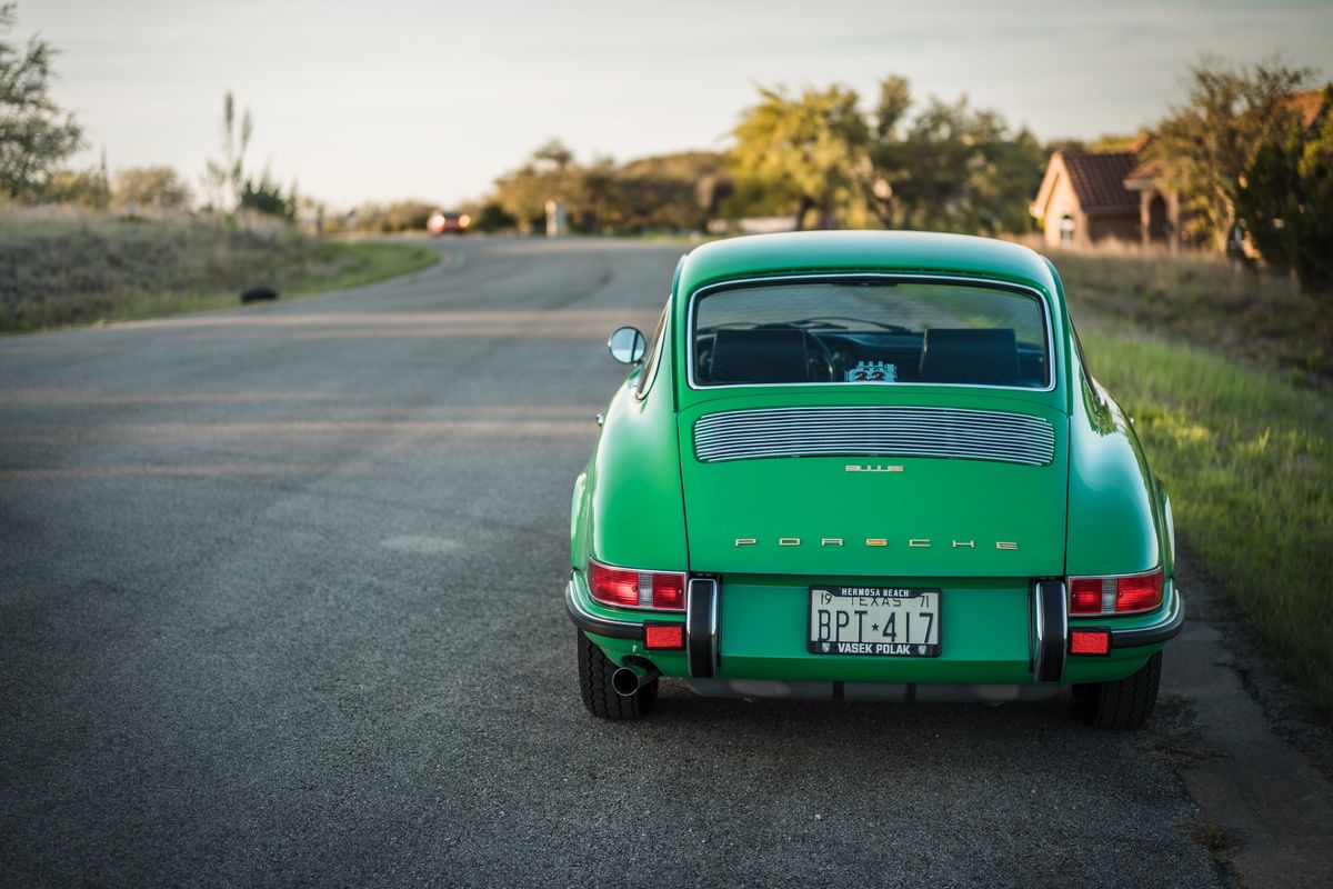 Rear angle of a Conda Green 1971 Porsche 911E, featuring classic chrome trim, 911E badge, and louvered engine lid.