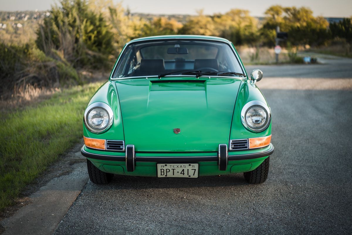 Front view of a vibrant Conda Green 1971 Porsche 911E. Features chrome headlight bezels, amber signals, bumper, and Texas '71 plate.