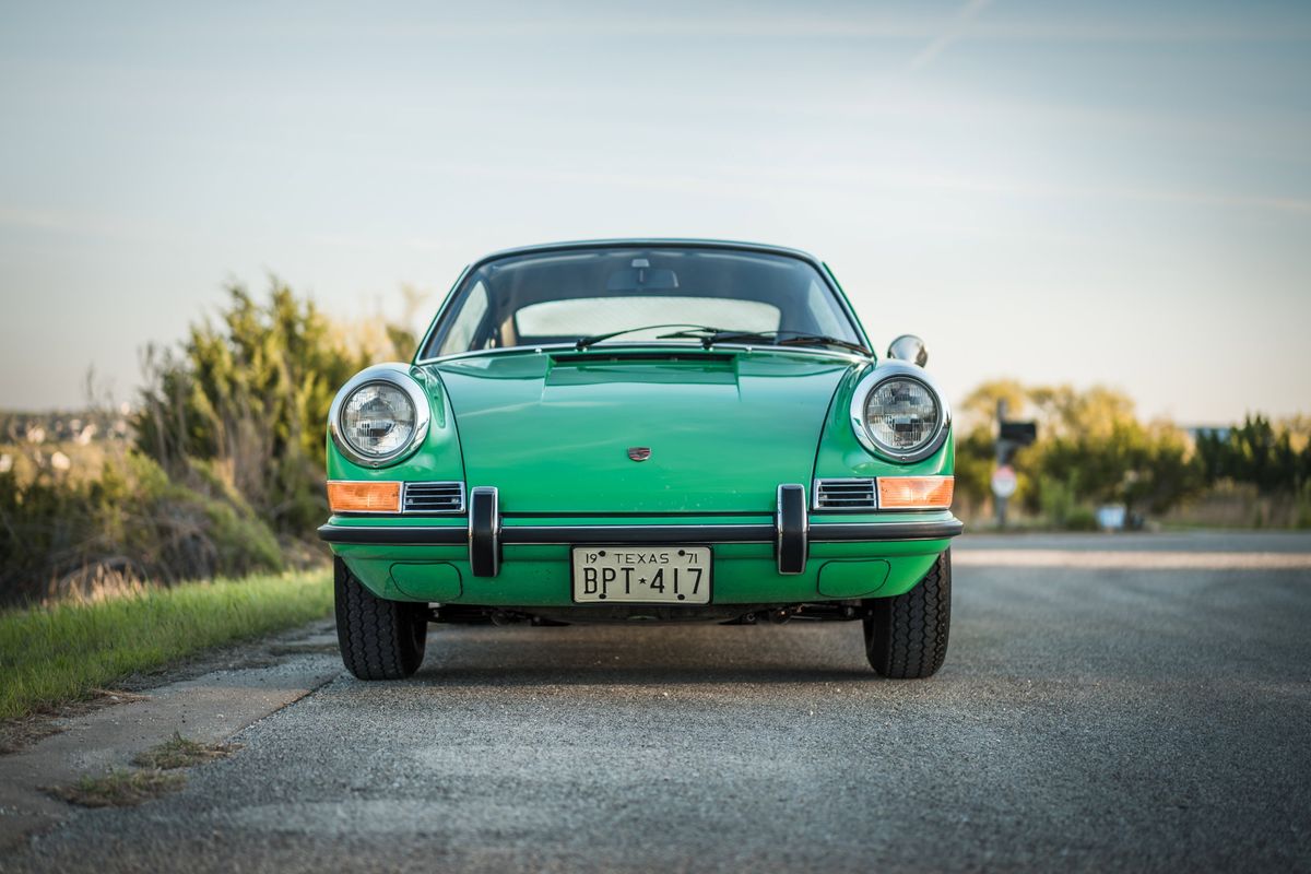 Front view of a Conda Green 1971 Porsche 911E with iconic chrome headlight bezels, bumper trim, and round amber turn signals.
