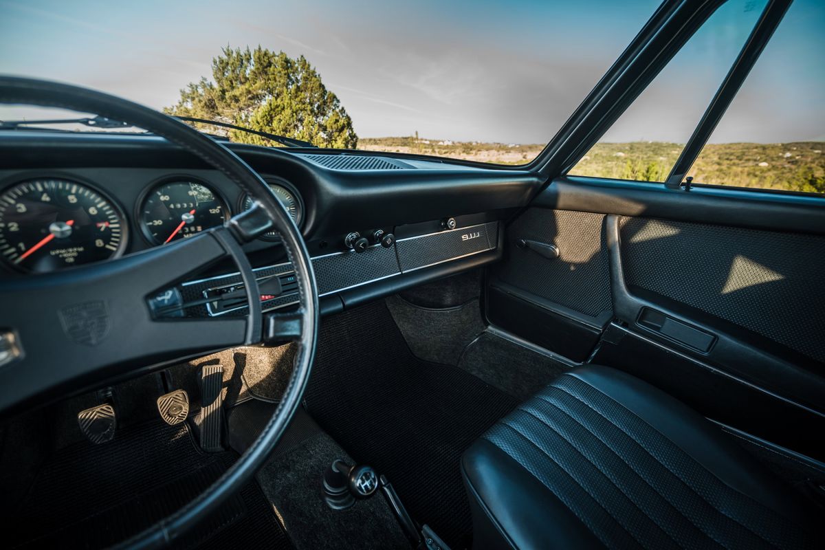1971 Conda Green Porsche 911E interior. Driver's POV: classic 5-gauge dash, "911E" script, manual shifter, & perforated trim.