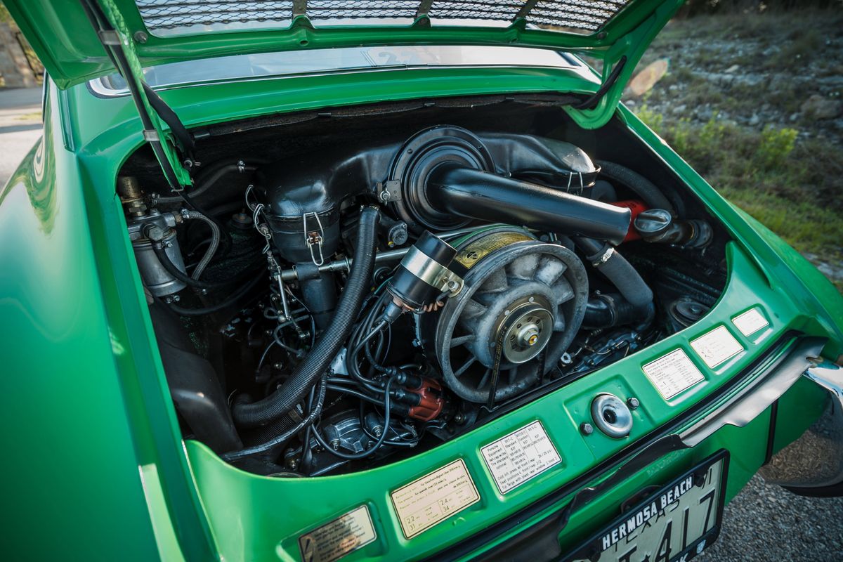 Close-up of a Conda Green 1971 Porsche 911E's open rear engine bay, revealing its iconic air-cooled flat-six engine.