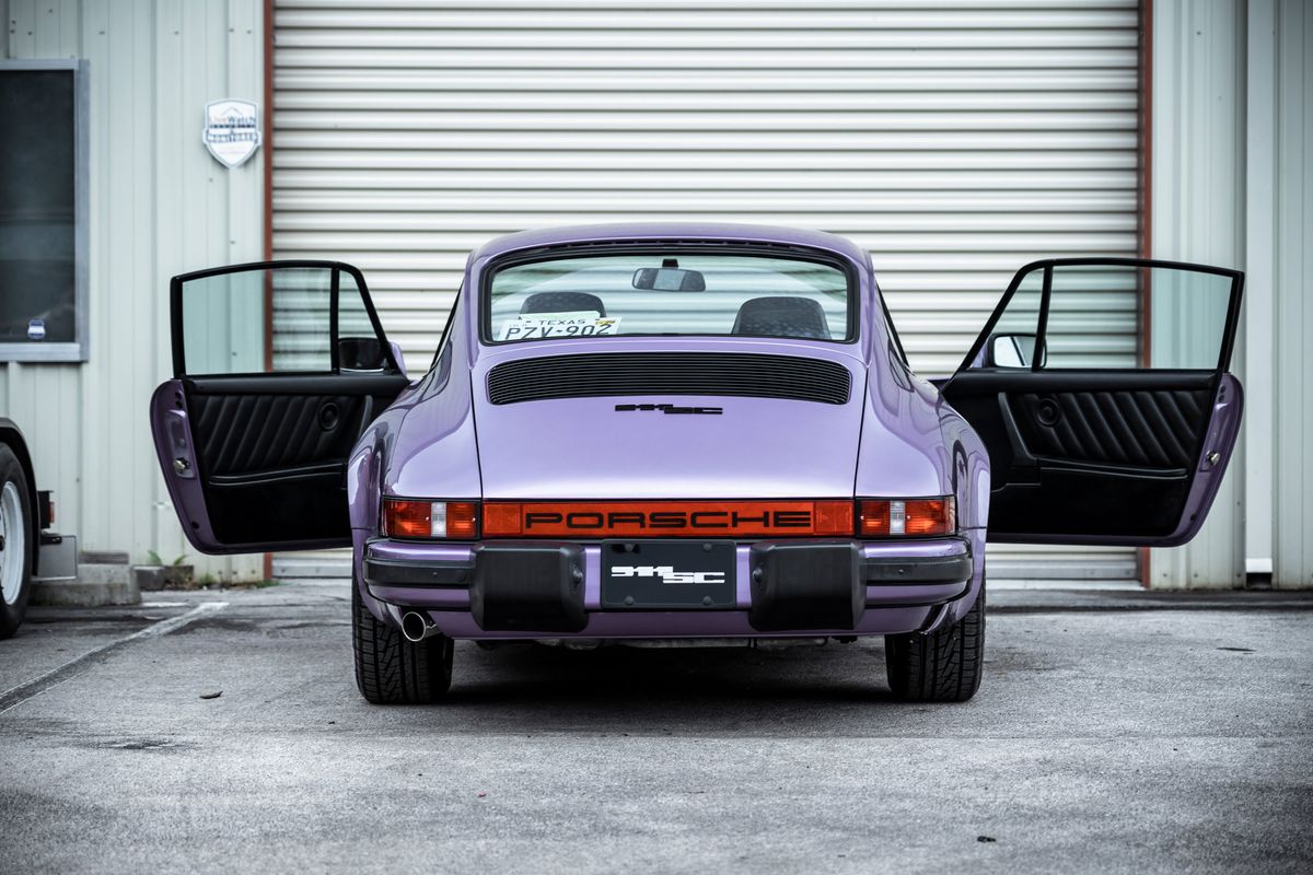 Vibrant purple Porsche 911SC (G-series) rear, doors open, showing black pleated interior and iconic PORSCHE reflector.