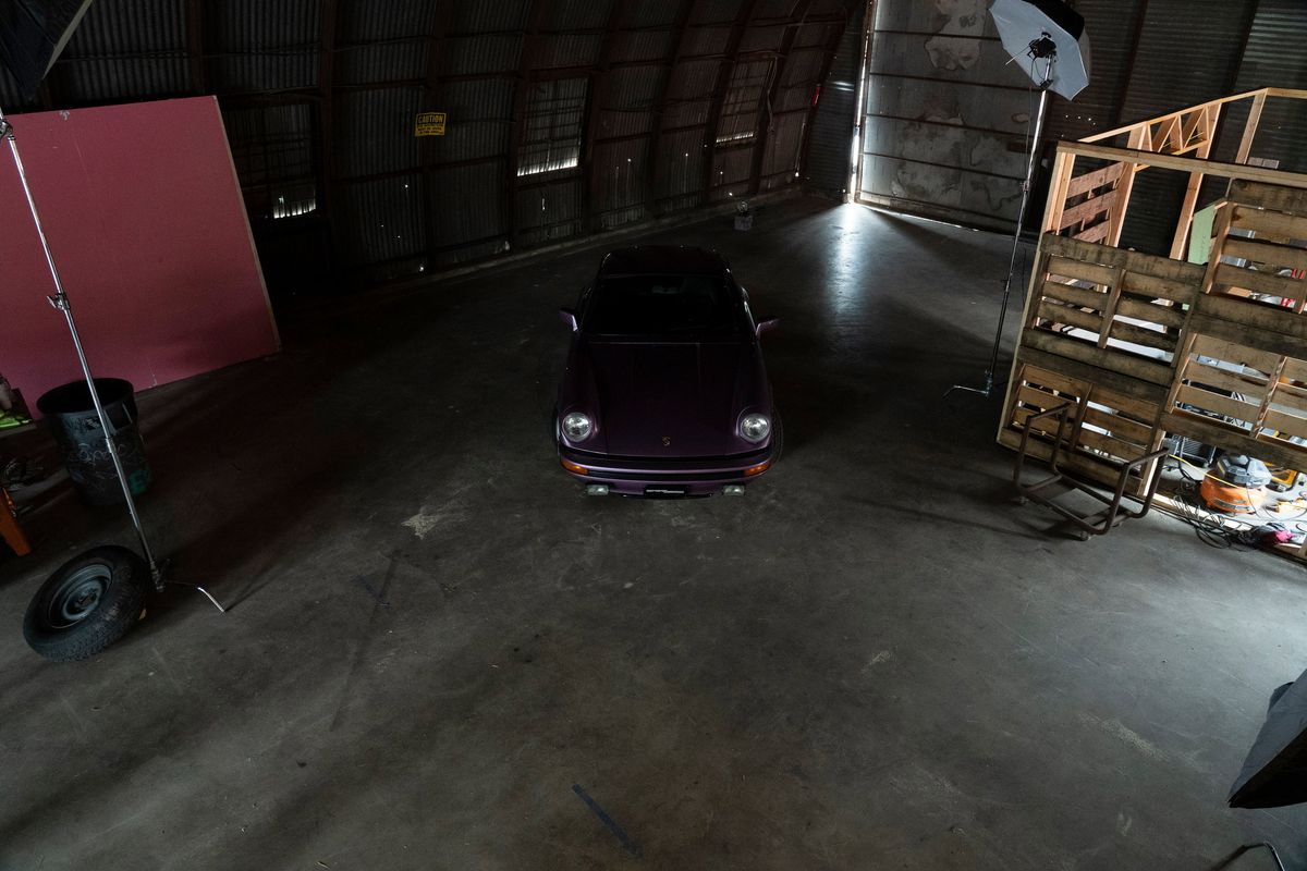 Aerial shot of a purple Porsche 964 911 coupe, highlighting its iconic round headlights and clean front fascia in a studio.