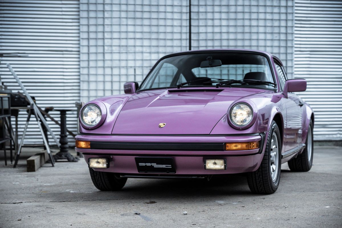 Vibrant purple Porsche 911SC, front view, showcasing its classic Fuchs rims, black bumper trim, and bright headlights.