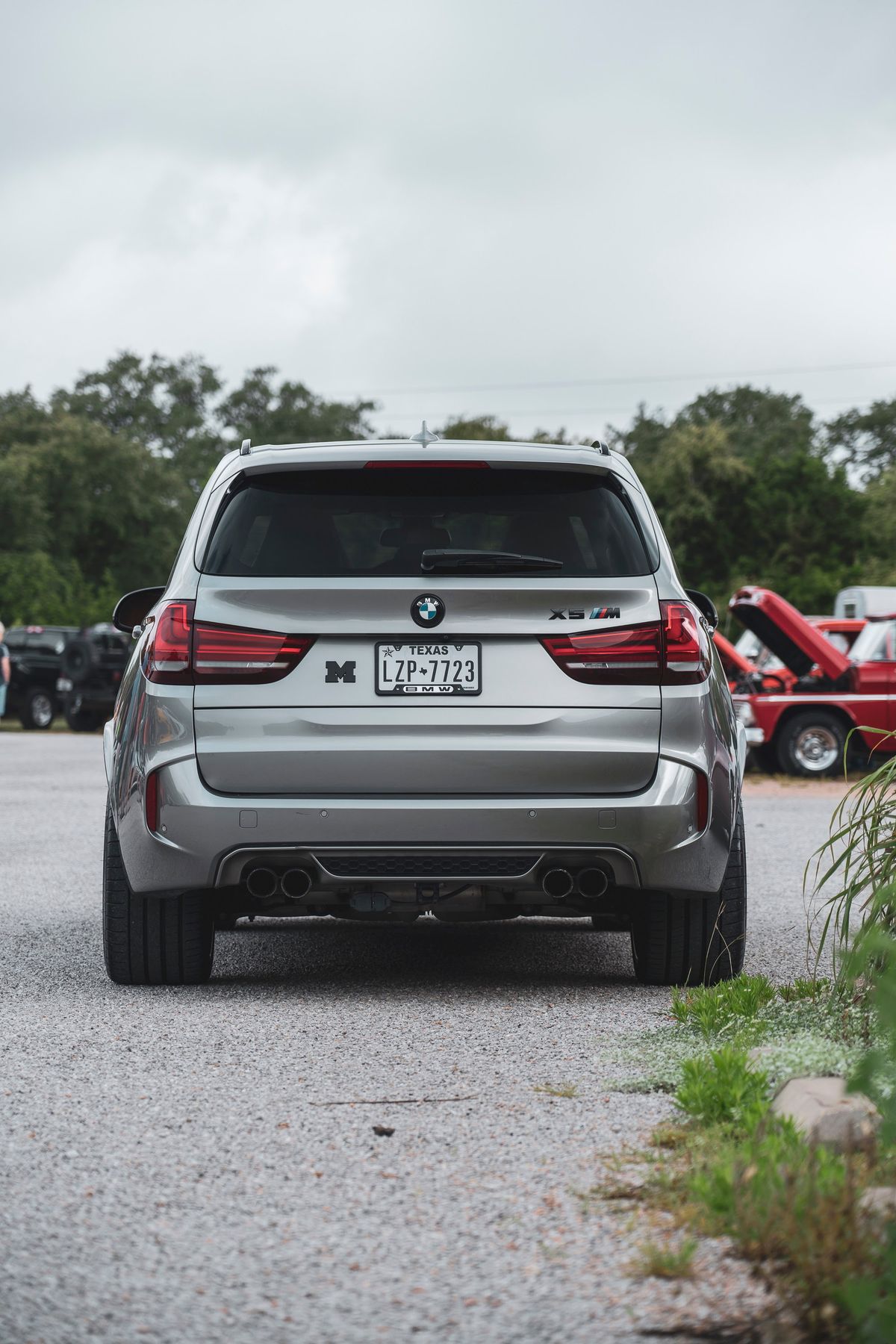 Rear view of a gray BMW X5 M performance SUV, showcasing its quad exhaust, aggressive rear diffuser, and wide tires.