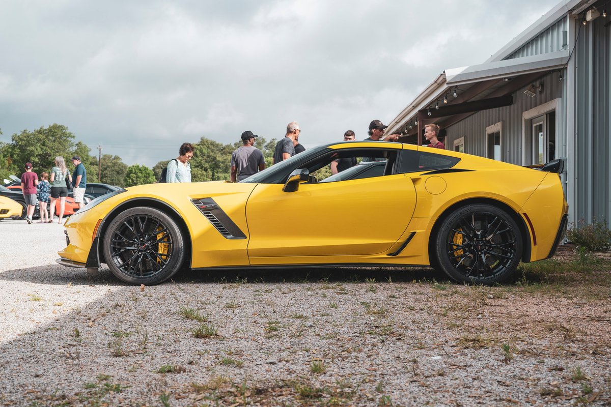 Bright yellow C7 Corvette Z06 in profile. Features black multi-spoke rims, yellow brake calipers, fender vents, and rear spoiler.