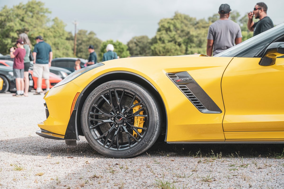 Yellow Corvette Z06 C7. Features black multi-spoke rims, yellow brake calipers, Z06 fender vent, and carbon fiber aero trim.
