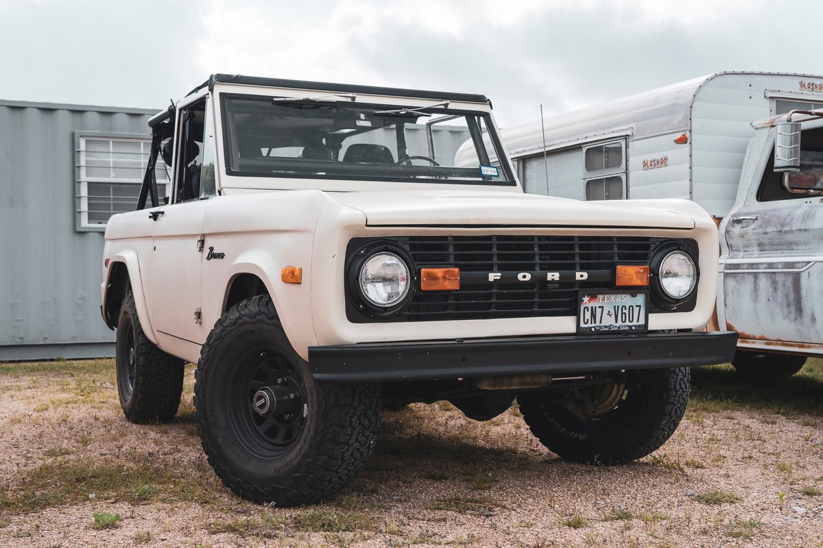 Vintage cream Ford Bronco 4x4 with black grille, off-road rims, and BFGoodrich All-Terrain KO2 tires. Topless retro SUV.