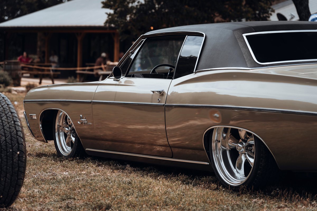 Bronze metallic 1968 Chevy Impala Custom coupe with black vinyl roof, chrome trim, polished multi-spoke rims, slammed.