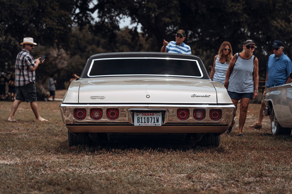Rear view: champagne metallic 1968 Chevrolet Impala coupe. Triple round taillights, chrome bumper & trim, dark vinyl roof.