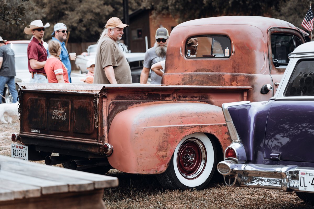 Rust patina Ford F1 pickup, pinstriped, with whitewall tires, deep red steelie rims & chrome trim at a car show.