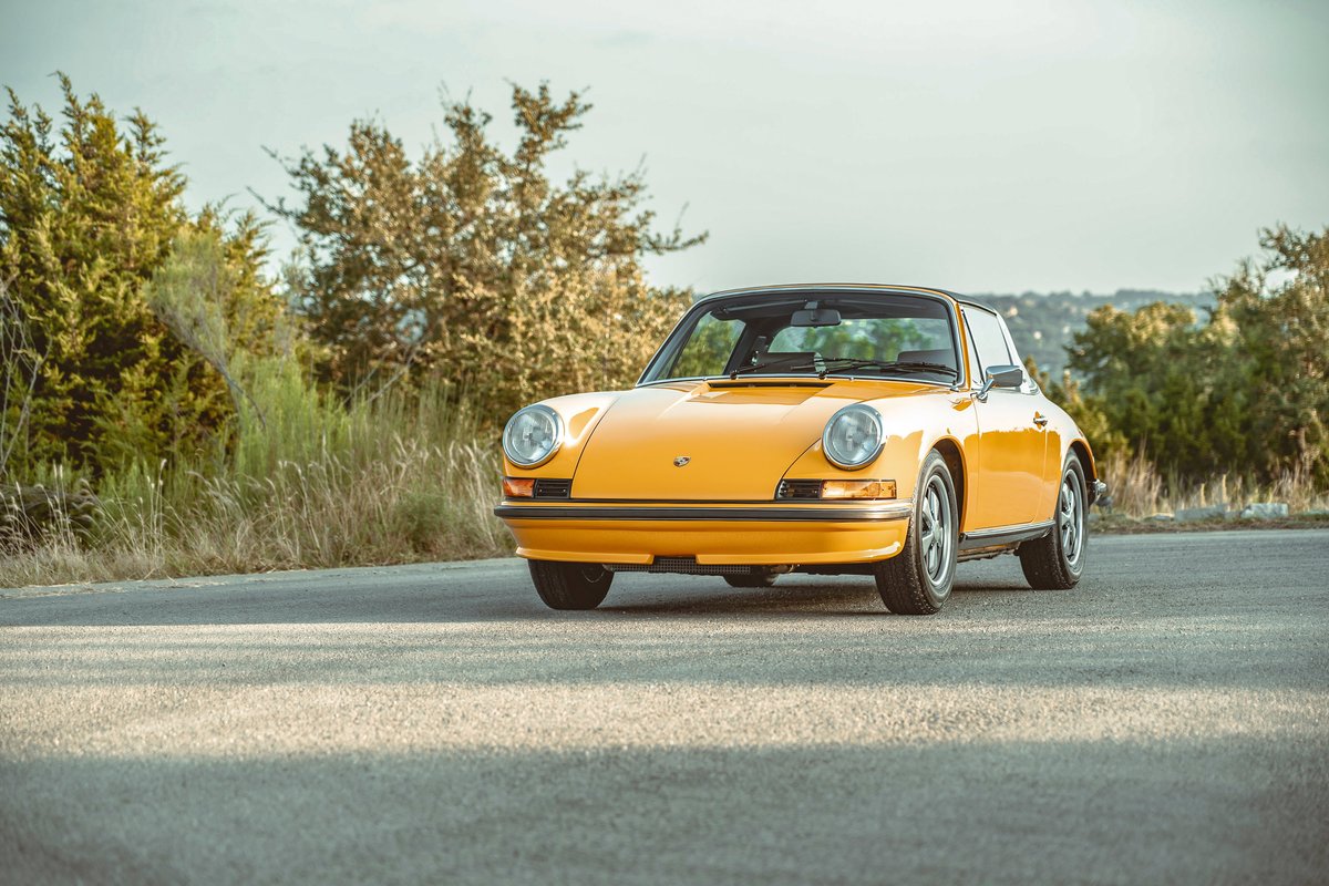 Vibrant Signal Yellow 1973 Porsche 911S coupe, showcasing its classic lines, chrome trim, and Fuchs alloy rims.