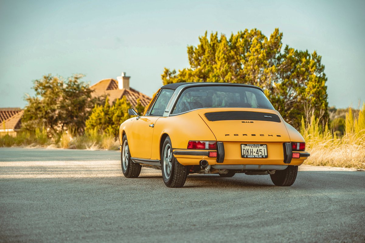 Signal Yellow 1973 Porsche 911S Targa. Rear three-quarter view, black roof, polished Targa bar, Fuchs-style wheels.