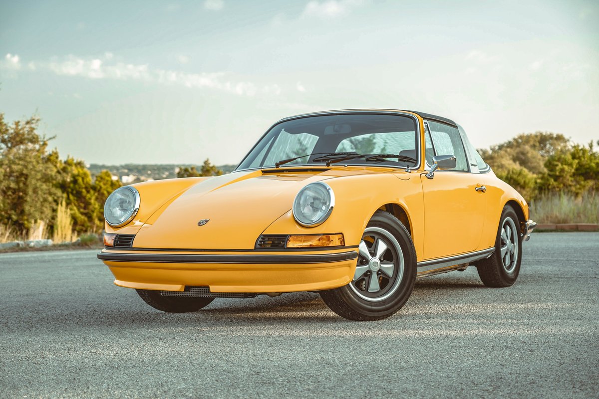 Signal Yellow 1973 Porsche 911S Targa. Features iconic Fuchs alloy wheels, chrome trim, and black Targa top.