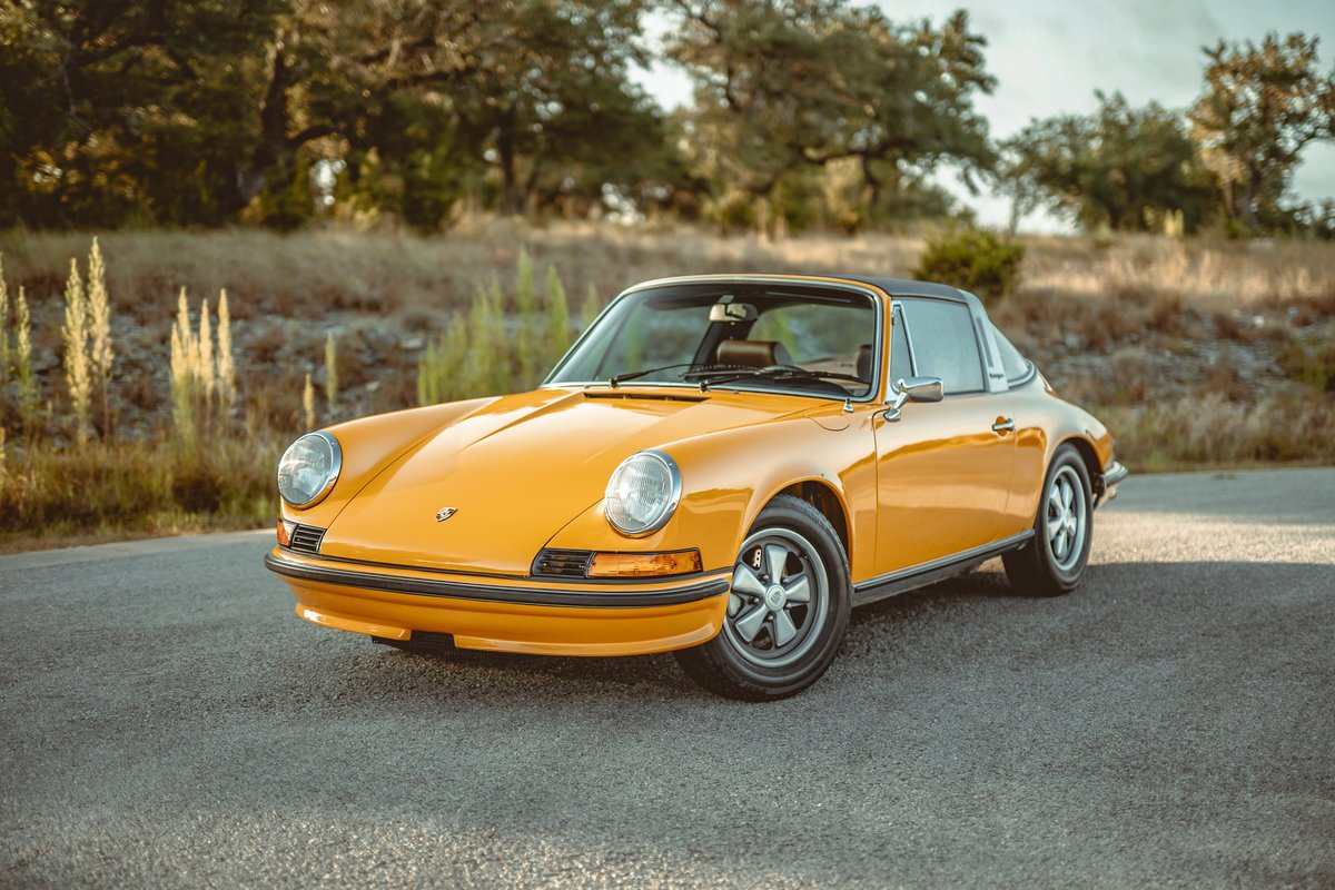 Front 3/4 view of a vibrant Signal Yellow 1973 Porsche 911S Targa, featuring iconic Fuchs alloy wheels and gleaming chrome trim.