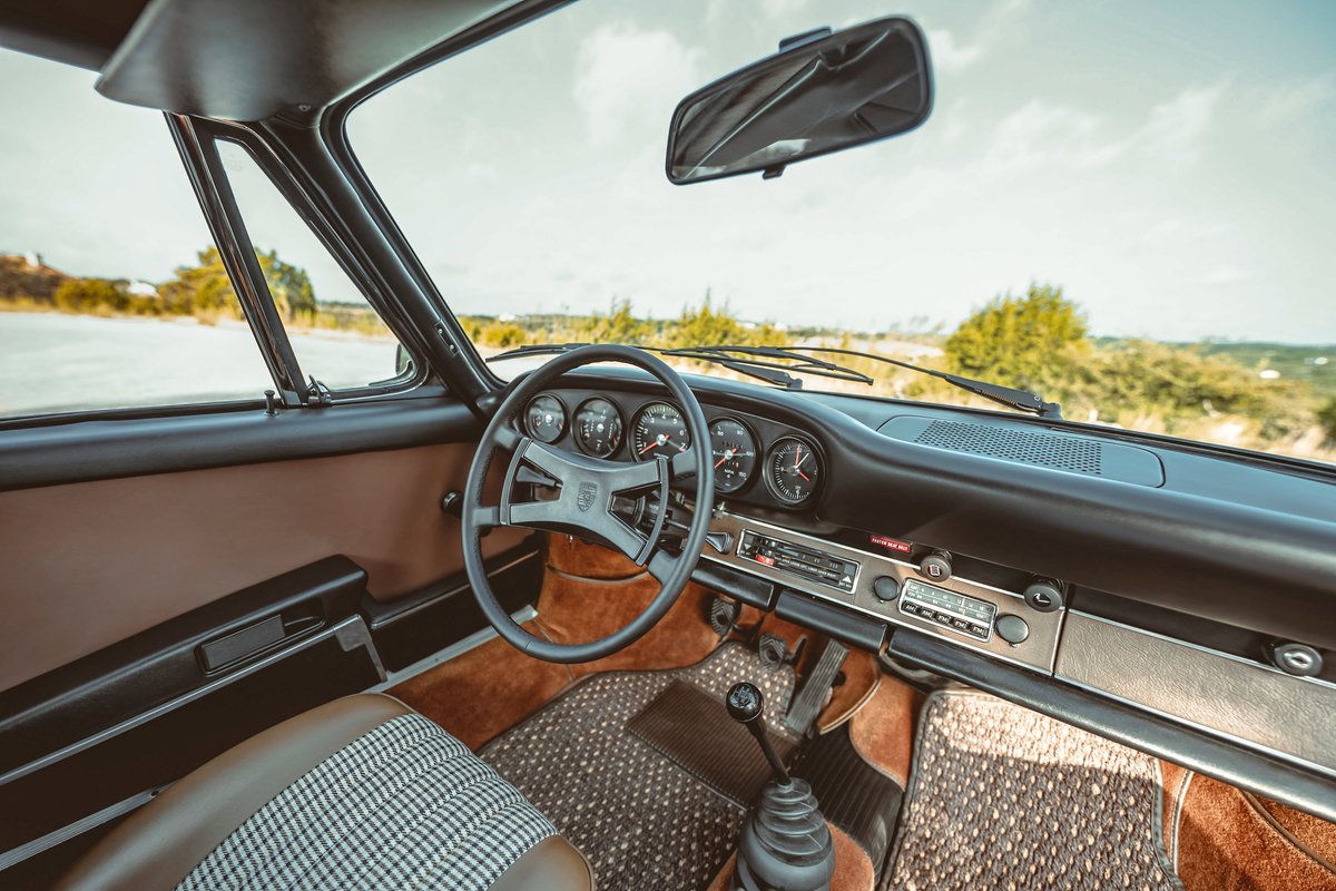 1973 Porsche 911S interior: brown trim, houndstooth seat inserts, classic 5-dial instrument cluster, period radio, manual shifter.