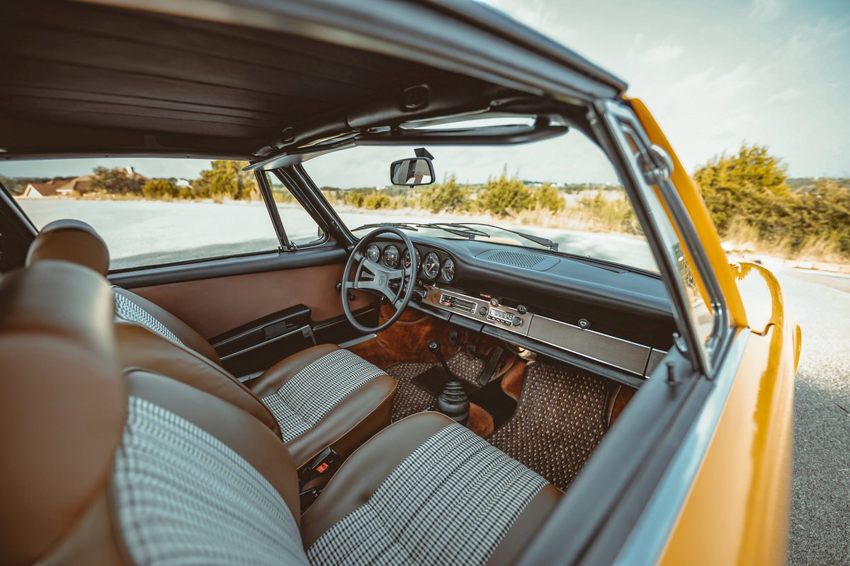 Interior of a 1973 Signal Yellow Porsche 911S Targa. Brown leatherette and pepita seats, classic dashboard, chrome trim.
