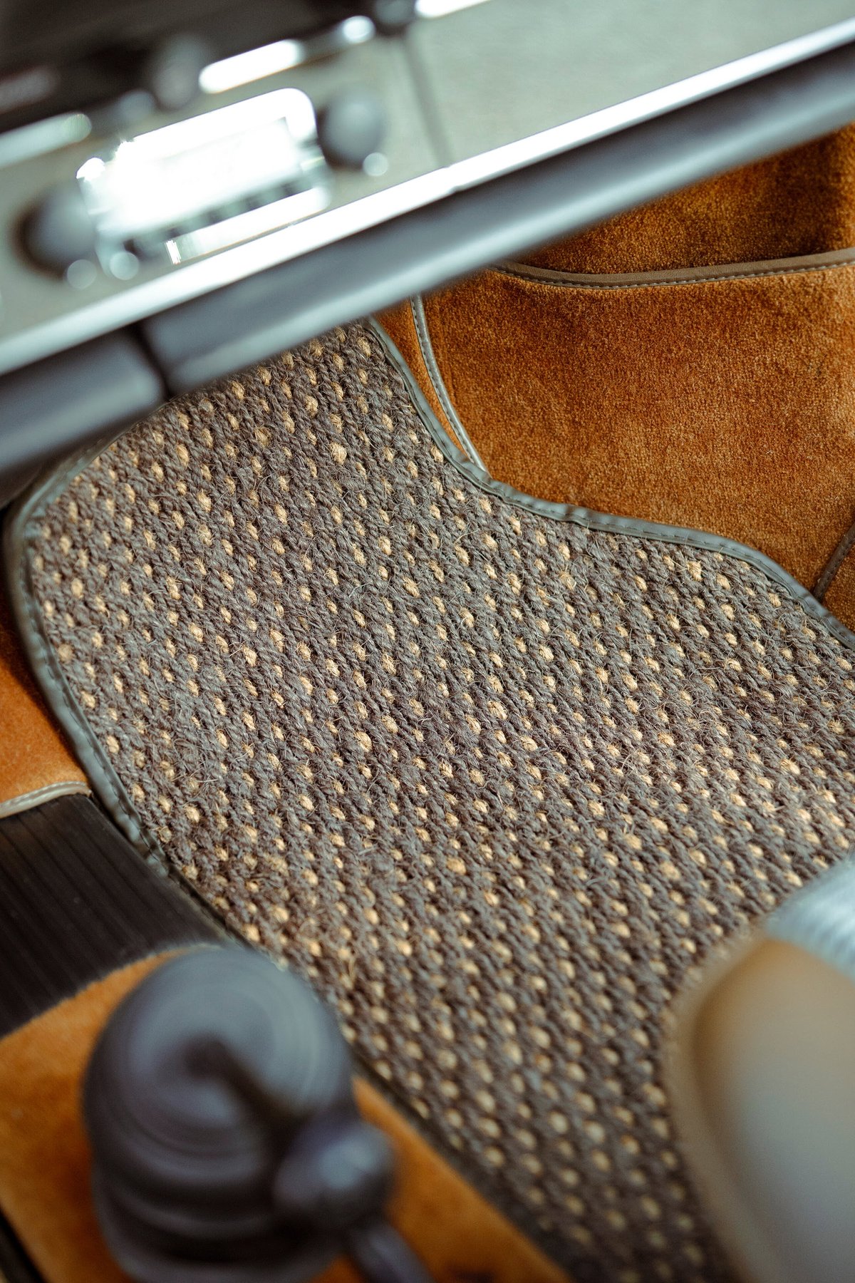 1973 Porsche 911S interior: detailed view of a classic brown coco mat, tan interior trim, and vintage dashboard controls.