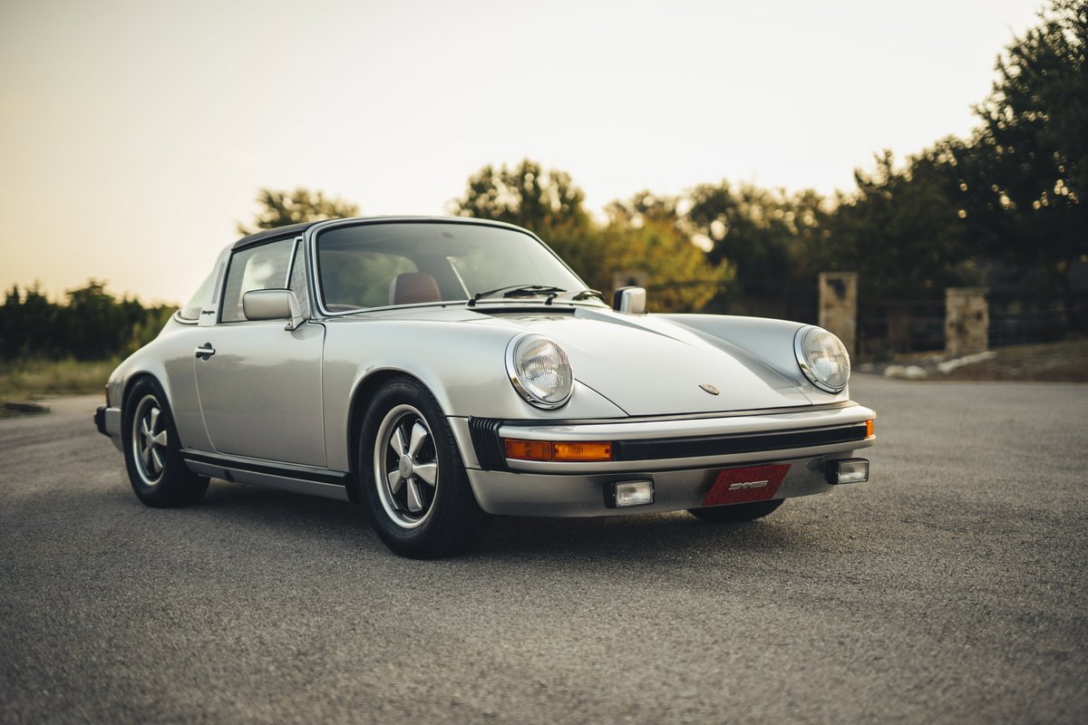 Silver Metallic 1977 Porsche 911S G-series Targa, featuring iconic Fuchs wheels, chrome trim, and a red interior.