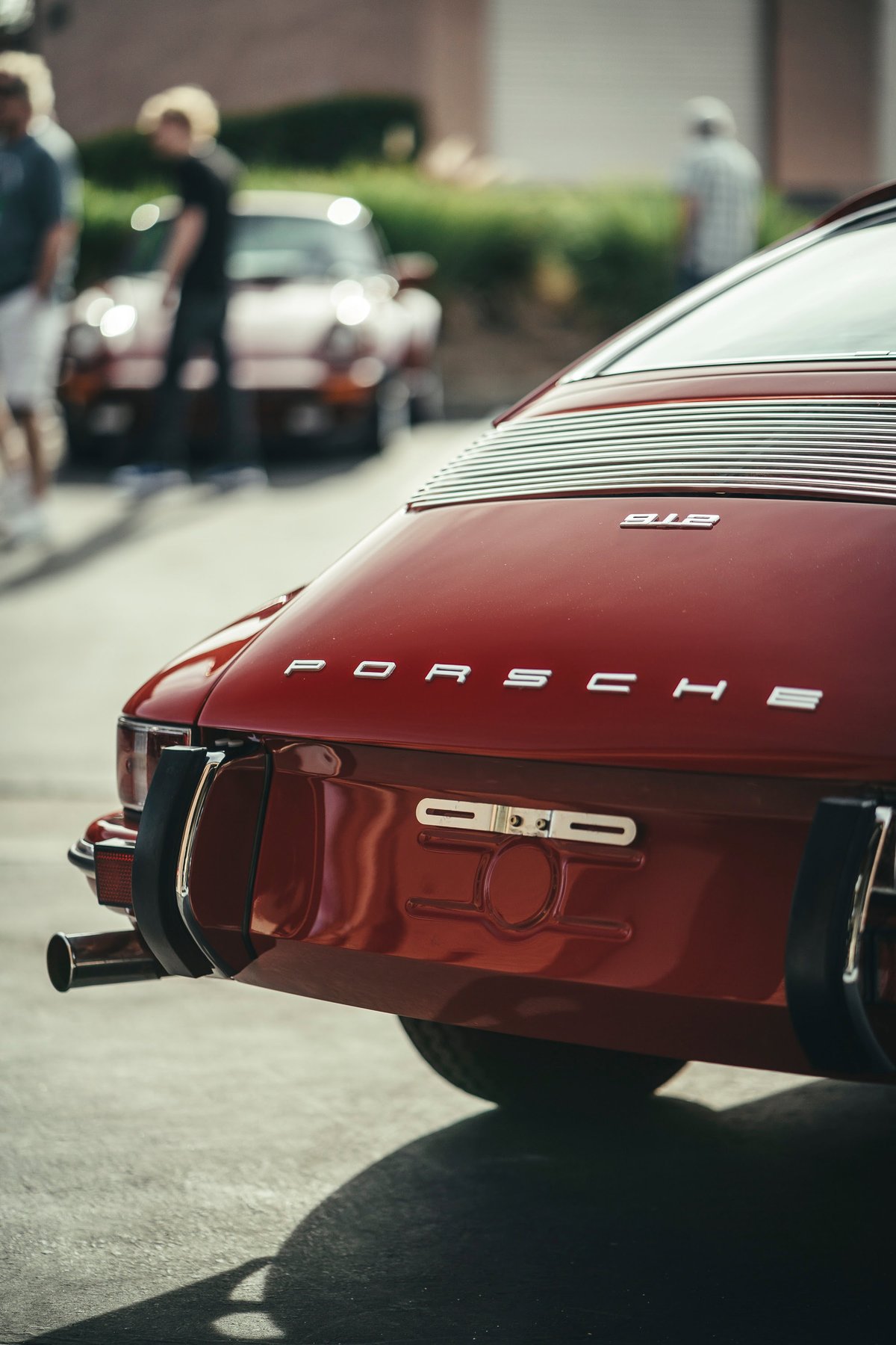 Deep red classic Porsche 911S rear, with 'PORSCHE' script, '911S' badge, slatted engine grille, and chrome trim.