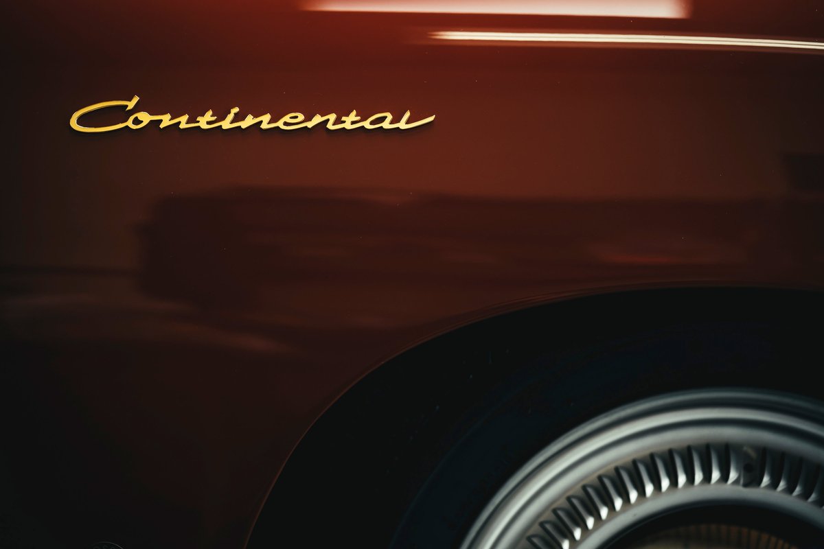 Deep metallic brown Lincoln Continental, with gold "Continental" script fender badge & classic ribbed wheel cover.