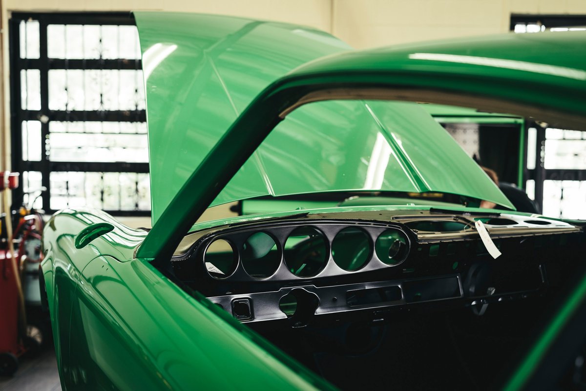 Sublime Green 1970 Dodge Challenger restoration. Open hood, stripped interior reveals classic dashboard gauge bezel cutouts.