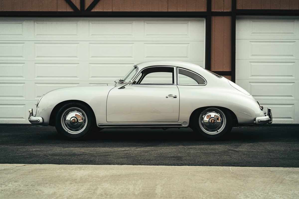 Silver Porsche 356 coupe with distinctive chrome trim, chrome bumpers, and shiny hubcaps. Classic car side profile by garages.