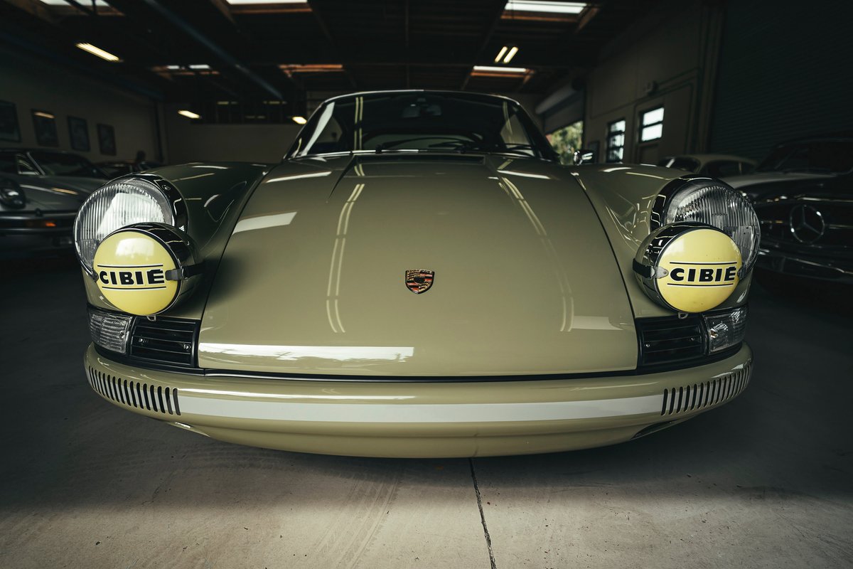 Front view of a classic '60s Porsche 911 in light green, featuring distinctive CIBIE rally lamps & white bumper livery.