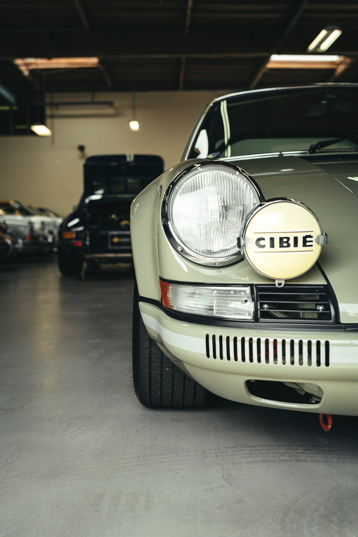 Lichtgrün classic Porsche 911 front fender, showing CIBIE rally light, white stripe livery, and red tow hook.