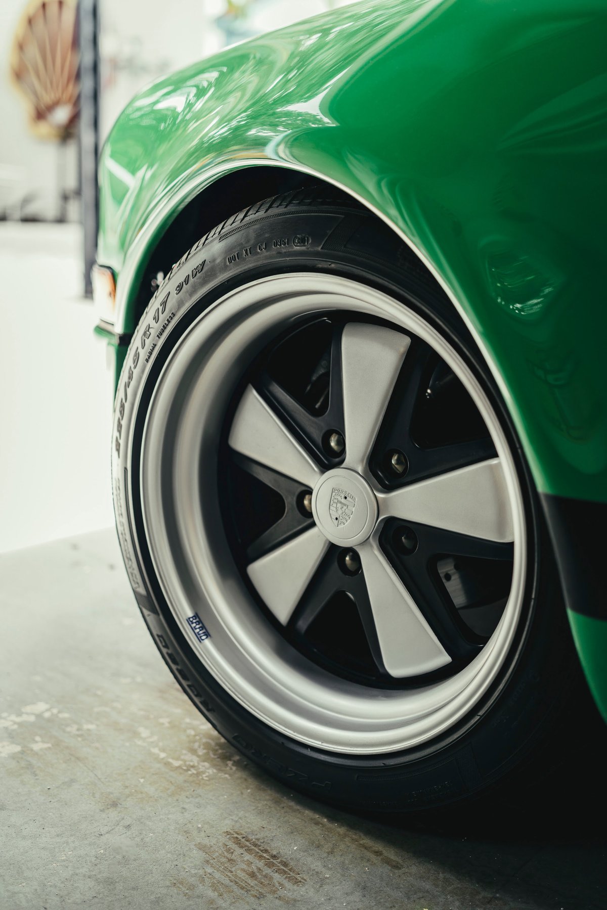 Viper Green Porsche 911 fender detail, featuring iconic Fuchs-style alloy rims with polished lips, black accents, and a side livery stripe.