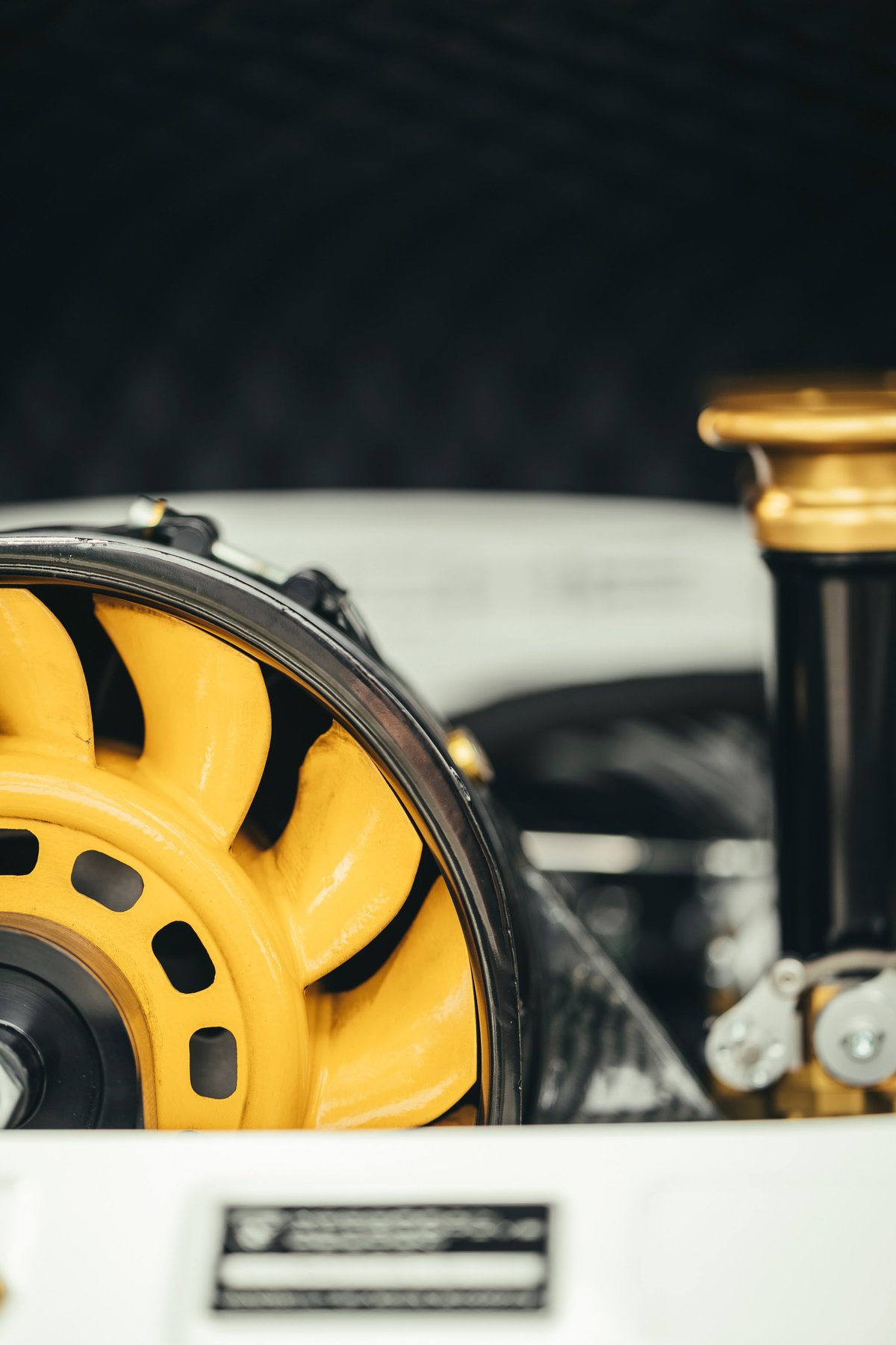 Lightweight sports car engine: vivid yellow centrifugal supercharger impeller in black housing, with gold trim details.