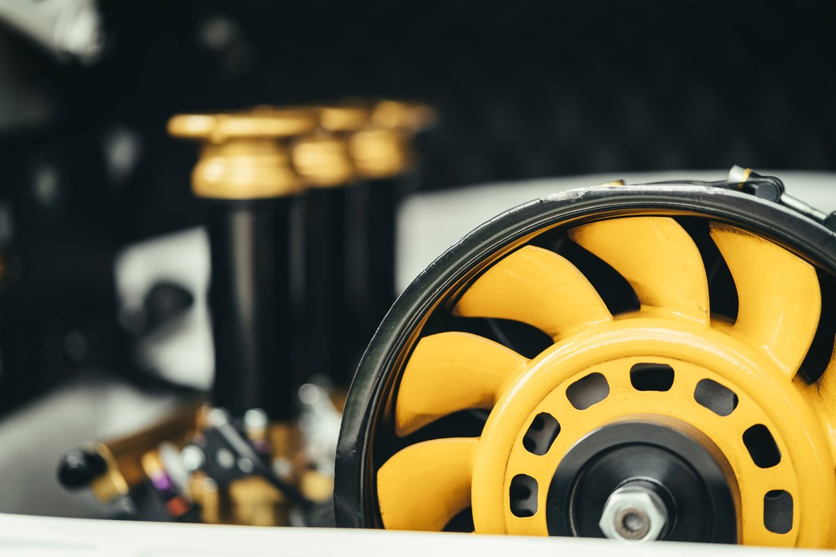 Detailed shot of a yellow Porsche 911 air-cooled engine cooling fan. Black fan housing and gold performance components visible.
