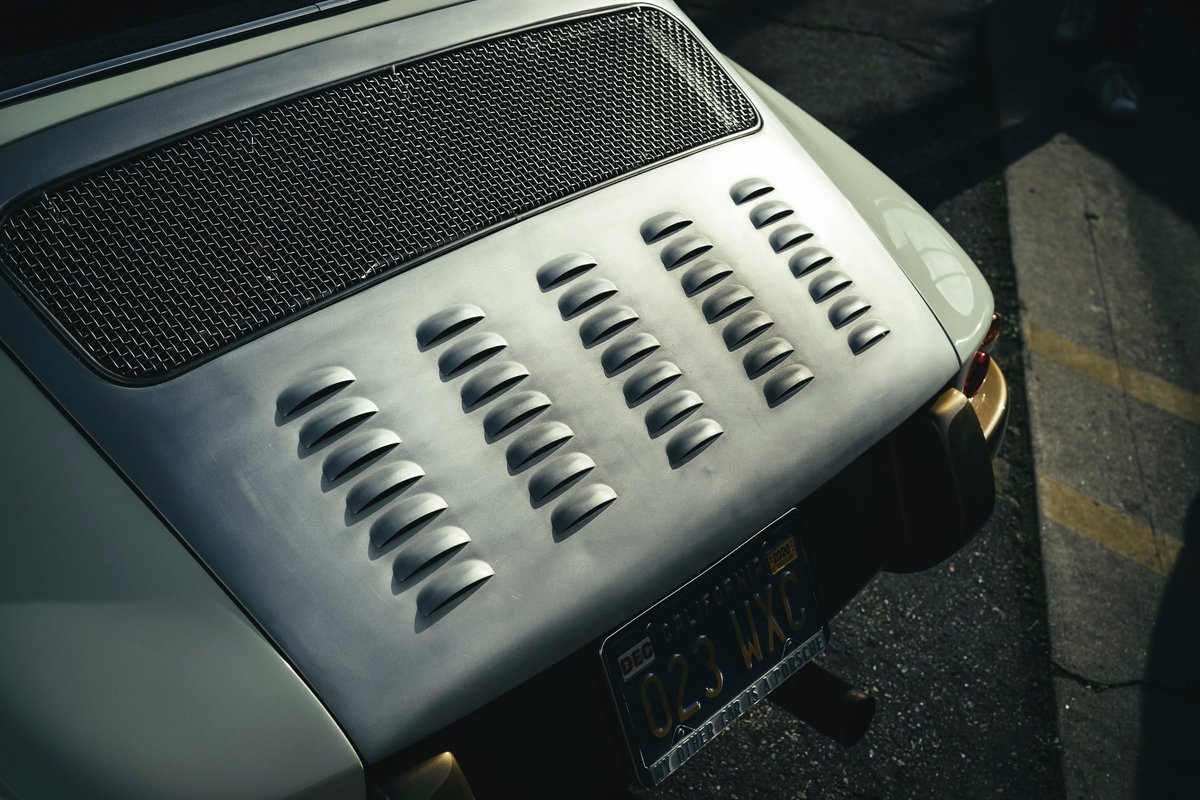 Modified vintage Porsche 911 louvered engine decklid with black mesh grille. Light grey panel for enhanced air-cooled performance.