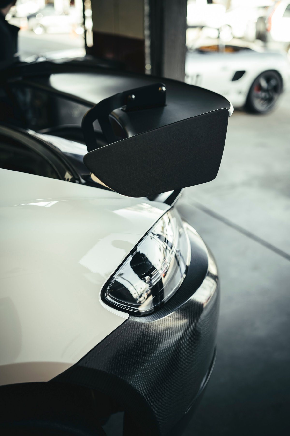 Close-up of a white Porsche 911 GT3 RS rear, showcasing its aggressive swan-neck rear wing and carbon fiber trim.