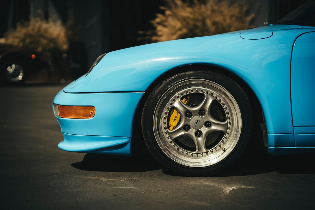 Bright blue Porsche 993 911 shows off RS multi-spoke rims with polished lips and vibrant yellow brake calipers.