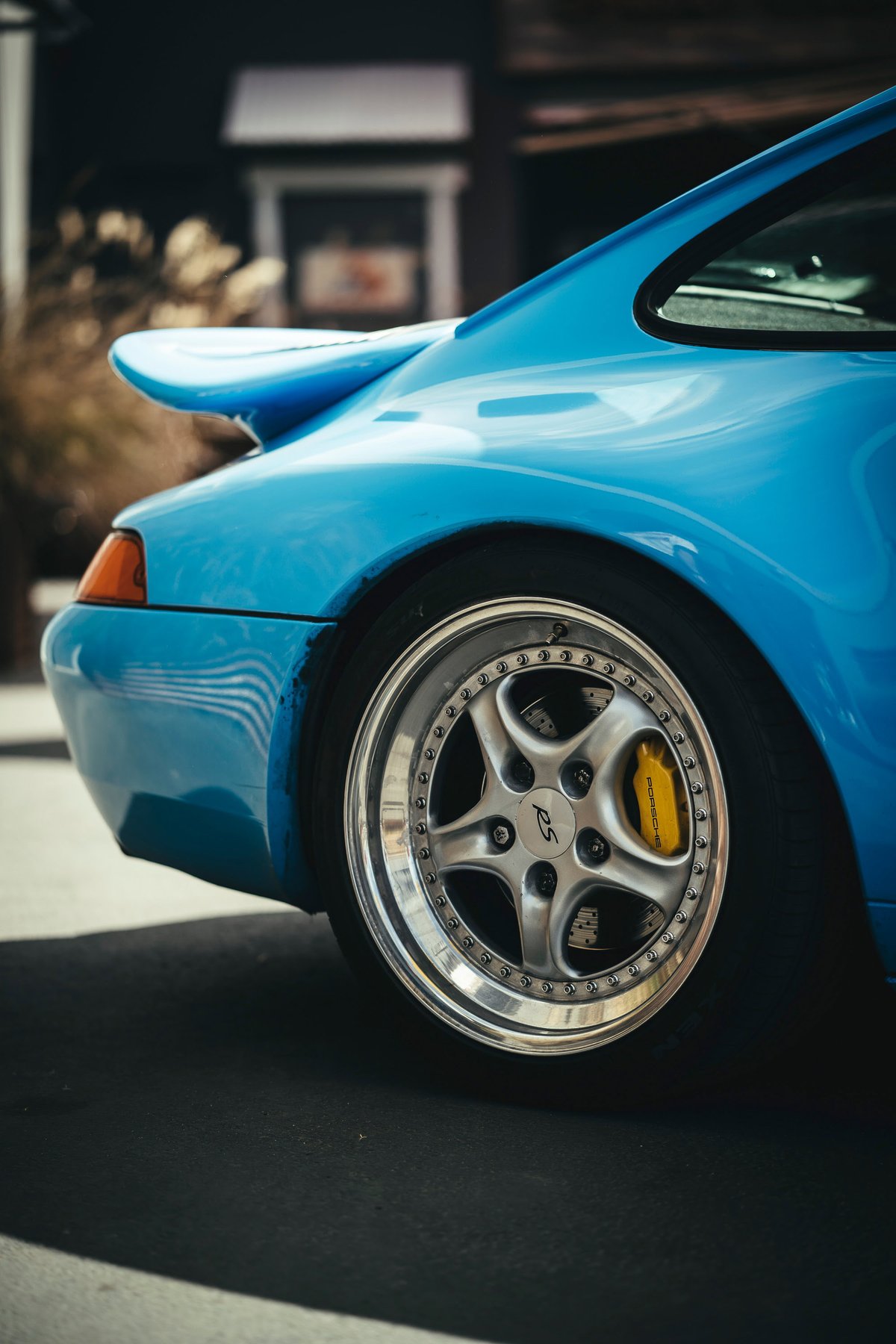 Riviera Blue Porsche 993 Carrera RS rear quarter view, featuring multi-piece Speedline-style RS rims, yellow Porsche calipers, and fixed wing.